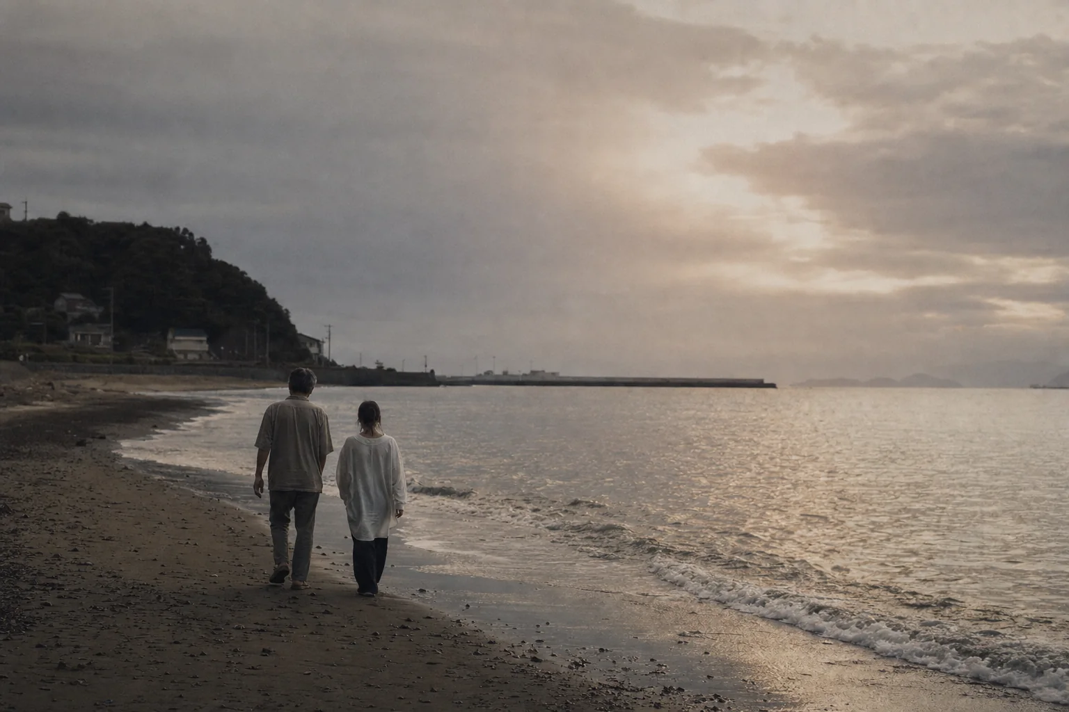 夕方の海辺を並んで歩く父と子の後ろ姿