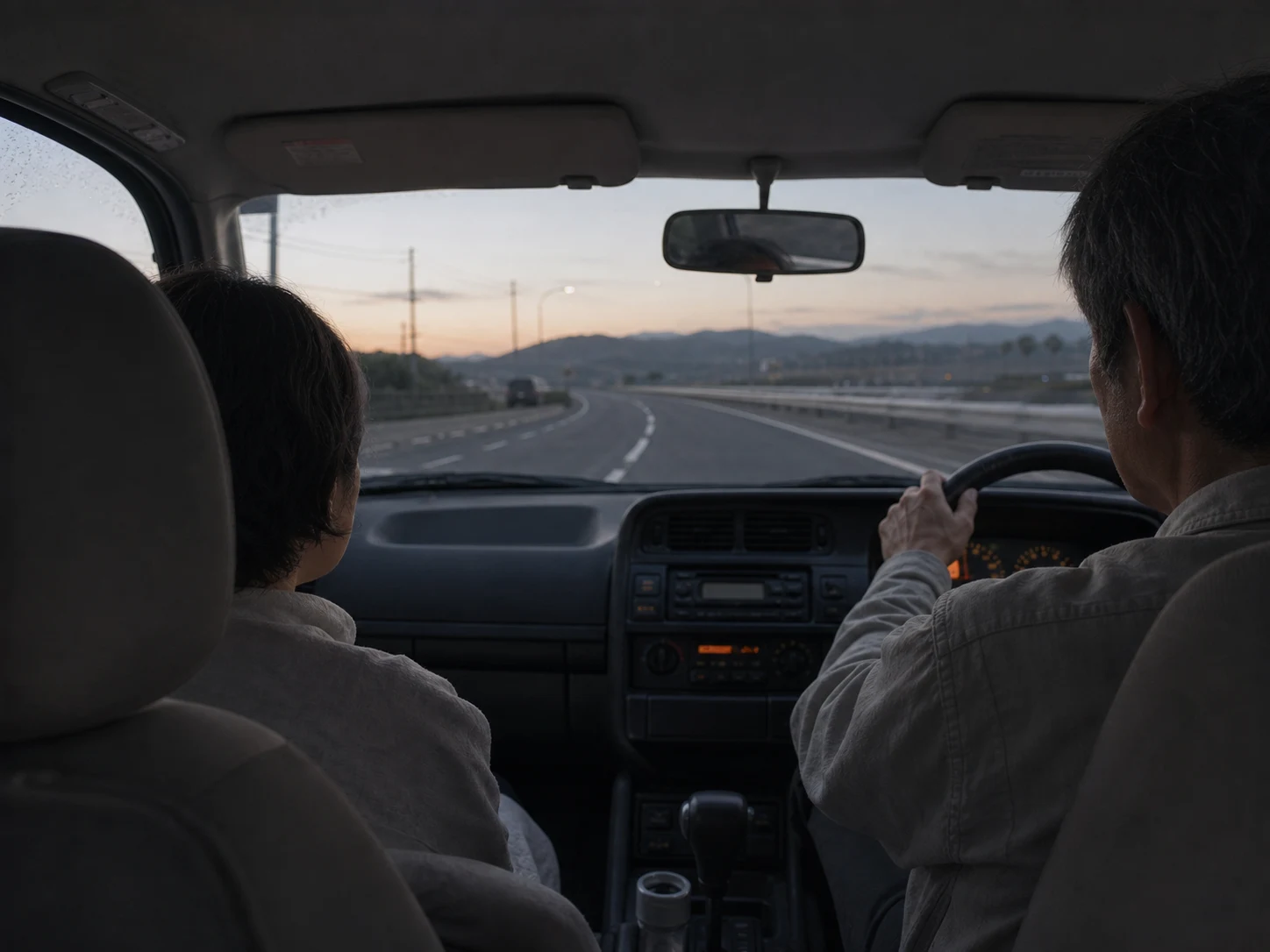 夜明けの高速道路を走る車内。父が運転し、母が助手席に座っている