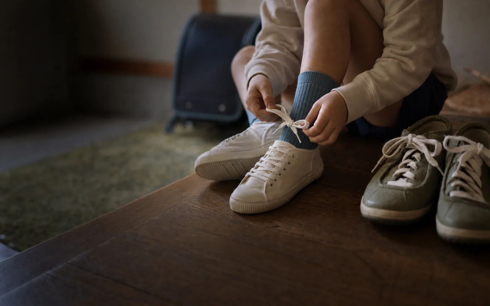入学前夜、子どもが自分の白い靴のひもを結び、隣に親の靴が並んでいる